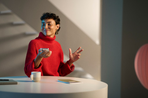 A woman smiles while listening to music from her phone through her paired hearing aids