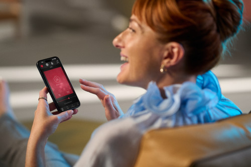 A woman smiles while using the ReSound app on her phone
